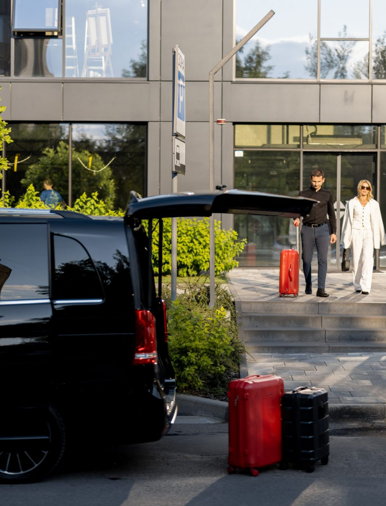 Driver or concierge helps a business couple carry their suitcases to the office or hotel from a minivan taxi. Concept of business travel and transportation service